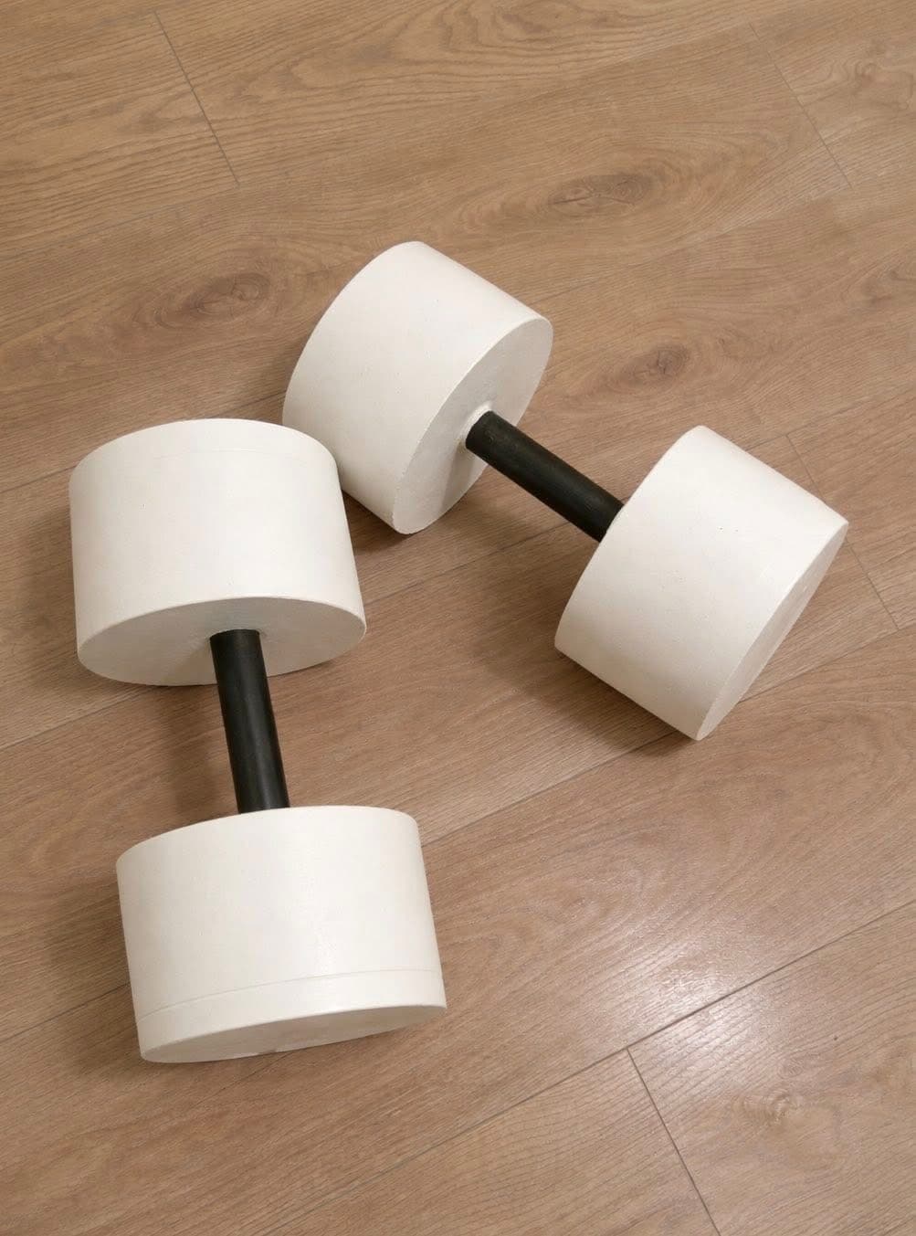 Cast concrete dumbbells standing on a light wood floor